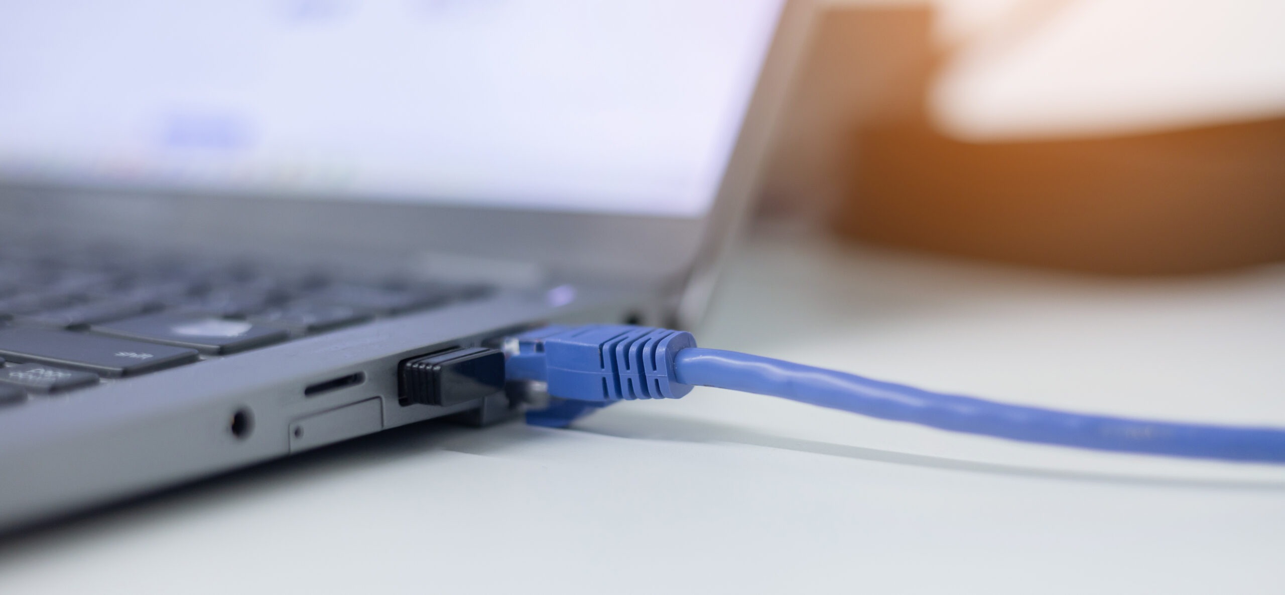 Laptop mit angeschlossenem blauem RJ45-Patchkabel
